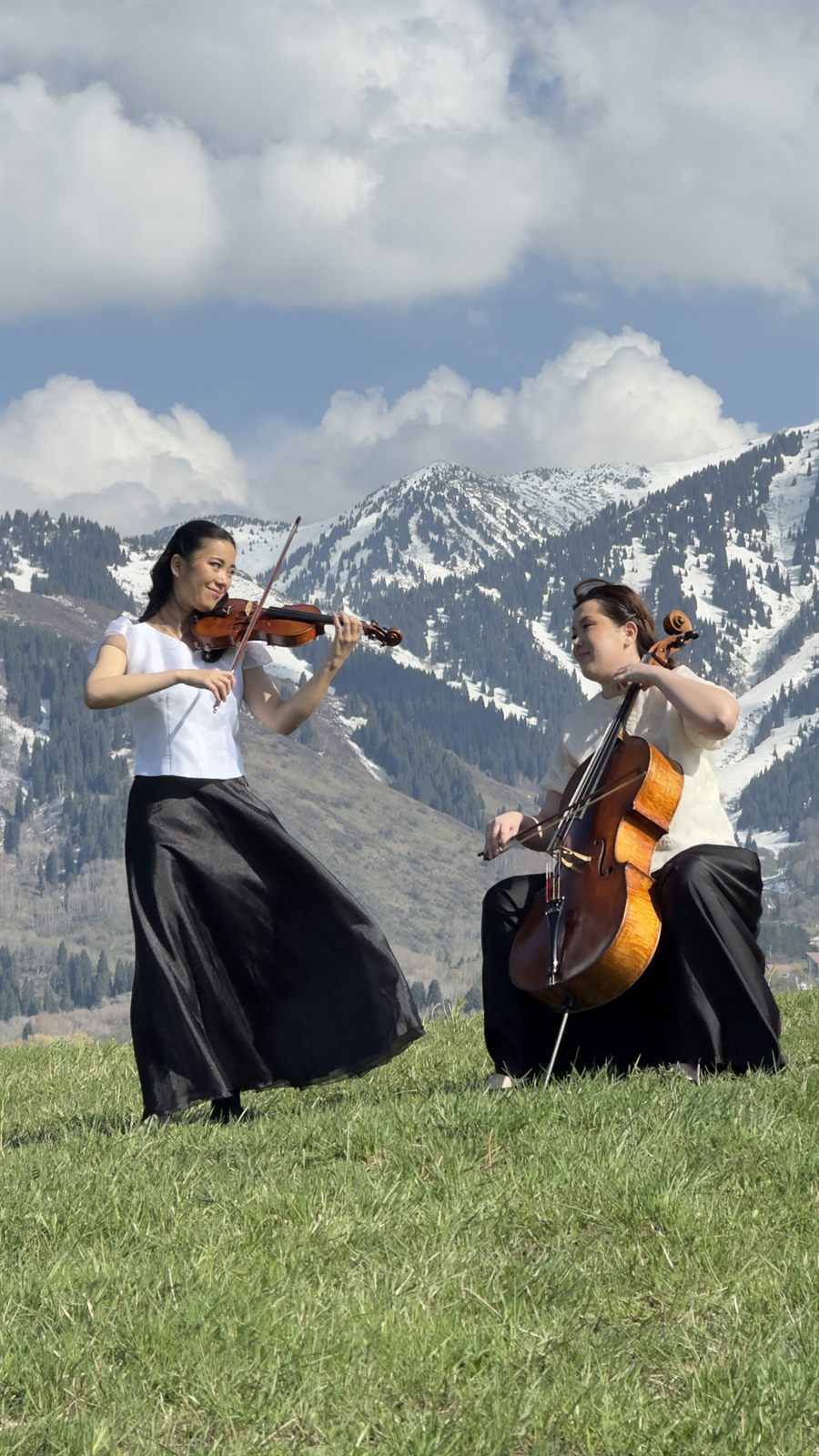 Violin and cello duo performing in the mountains